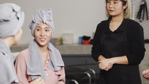 Two Asian girls in white bathrobes with towels on heads talking salon spa