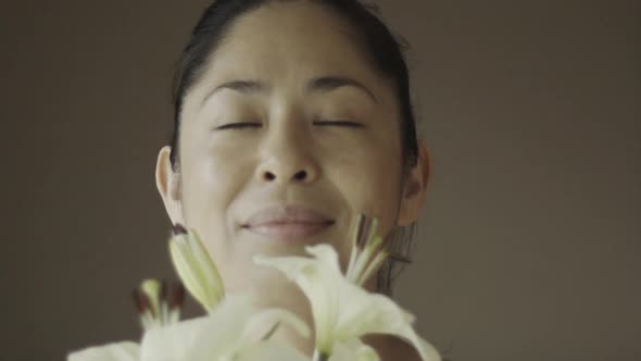 Slow motion view of woman smelling lilies