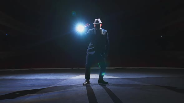 Artist dancing on scene. Theatrical man in elegant suit and hat performing on stage in spotlight