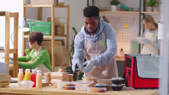 Black Man Packing Meals and Drinks in Food Delivery Bag