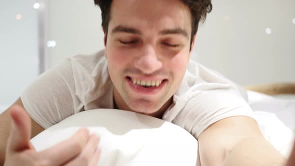 Inviting Gesture by Handsome Young Man lying in bed