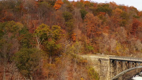 pedestal shot as the drone camera pans right, rises & dolly left, above the waterfalls & overpass. I