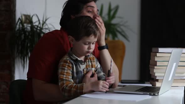 Father working with a son in home office at laptop