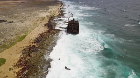 Aerial approach to the rusty wreck standing on top of the reef on Klein Curacao island in the Caribb