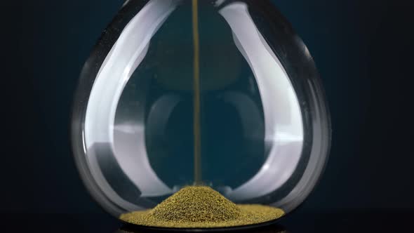 An Hourglass Made of Yellow Metal Shavings Passes Through a Funnel Symbolizing the Concept of Time