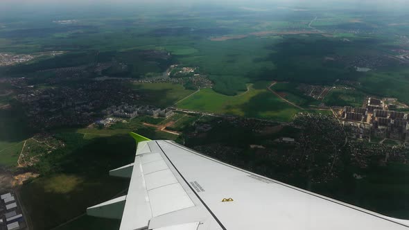 View From the Window of the Plane with Green Lands and Buildings on the Earth