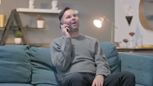 Casual ManTalking on Smartphone on Sofa