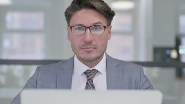 Close Up of Middle Aged Businessman with Laptop Showing Thumbs Down