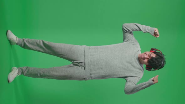 Full Body Of Asian Man Listening To Music With Headphones And Dancing In The Green Screen Studio