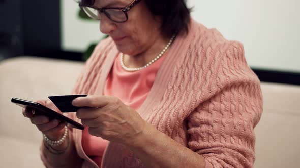 Senior Woman Using Mobile Phone And Credit Card Shopping Online Outdoors. Woman Online Banking.