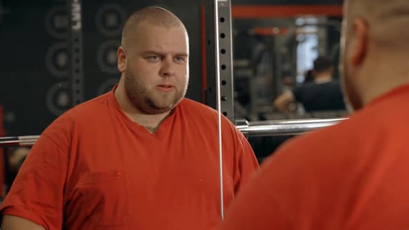 Overweight Man Holding Barbell in Hands and Workout in Gym