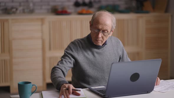 Old Person is Calculating His Expenses and Planning Budget Sitting at Home Counting By Calculator