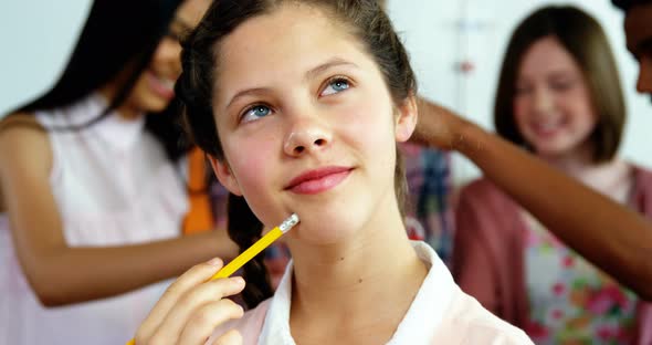 Thoughtful schoolgirl holding pencil in laboratory