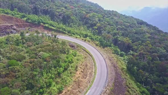 Drone Flies Above Mountain Road Curve Among Woods