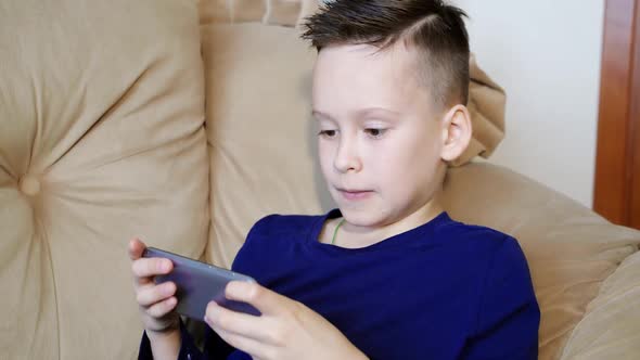Good kid is playing on his smartphone and becoming nervous when loses.