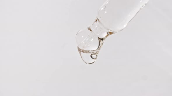 Cosmetic Pipette with Drops of Oil Close Up on White Background