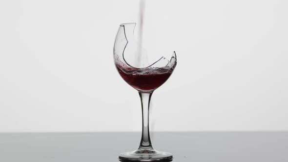 Wine. Red Wine Pouring in Broken Wine Glass on the Wet Surface
