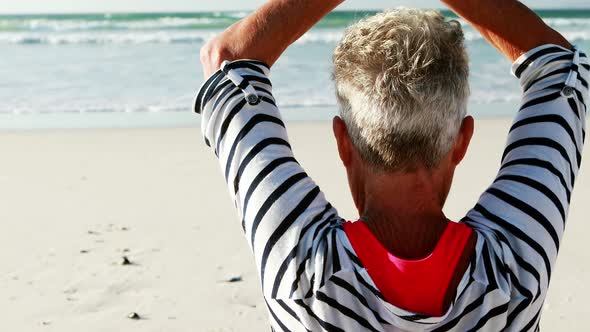 Senior woman doing yoga on the beach