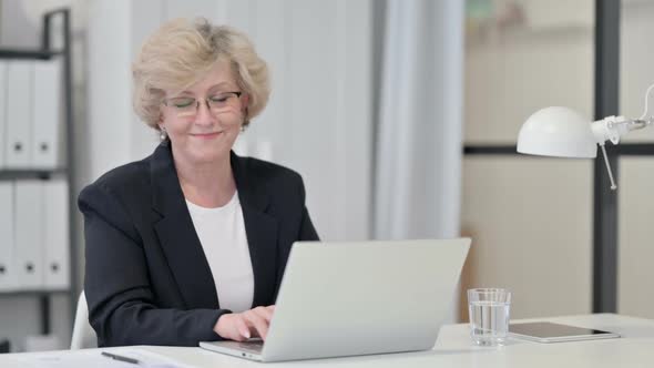 Old Businesswoman with Laptop Smiling at the Camera