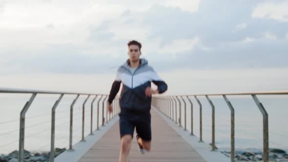 Young attractive athlete running to the camera on a Bridge in the morning from a perspective point o