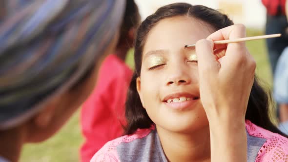 Woman applying paint on girl eyebrows 4k