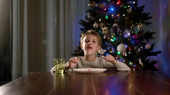 New Year, Funny Boy Sitting At The Table And Eats The Sausage