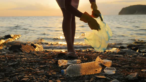 Hand Woman in Yellow Gloves Picking Up Empty Plastic Bottles Cleaning on the Beach