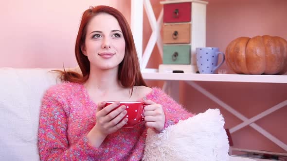 Redhead girl cup sitting on sofa at home