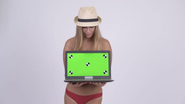 Happy Young Beautiful Blonde Tourist Woman Thinking While Showing Laptop