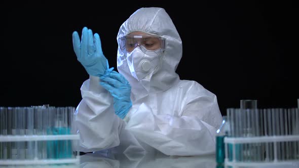 Laboratory Assistant Wearing Protective Suit and Studying Test-Tubes With Virus