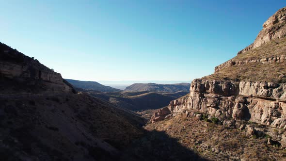 Drone aerial view panning to the left of a large valley with cliffs