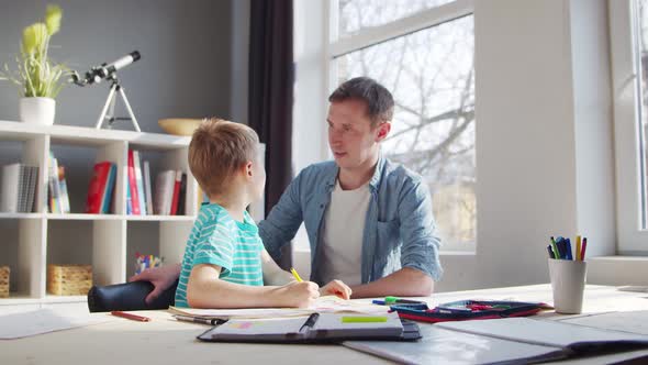 Boy and Father Doing Homework at the Table. Child is Learning at Home.