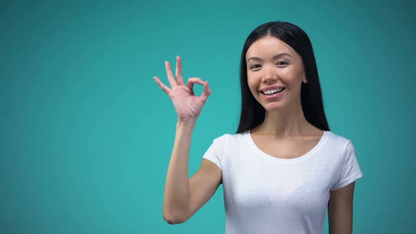 Cheerful Asian Woman Showing Ok Sign, Isolated on Blue Background, Template