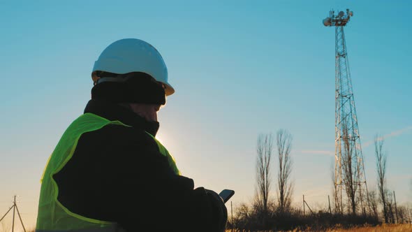 Silhouette Engineer Working on Satellite Dish Telecom Network on Telecommunication Tower in Sunset