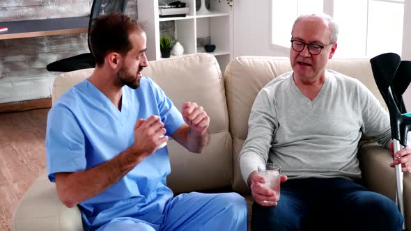 Young Doctor Helping Old Man in Nursing Home