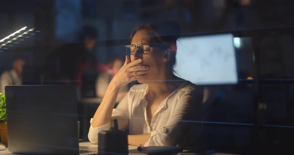 Exhausted Businesswoman Working Late Night at Laptop in Office