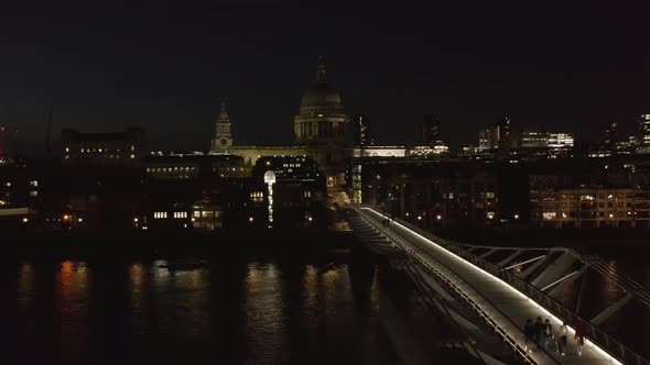 People Walking Across Millennium Bridge at Night