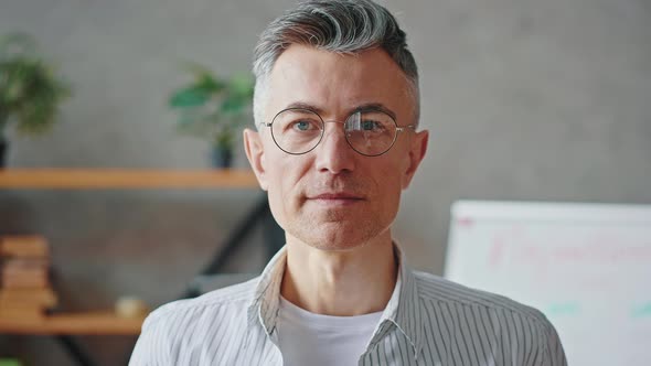 Close Up Portrait of Confident Mature Greyhaired Man in Eyeglasses Looking at Camera and Smiling