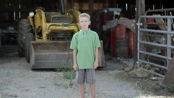 Slow motion push of boy with cleft lip standing in front of tractor.