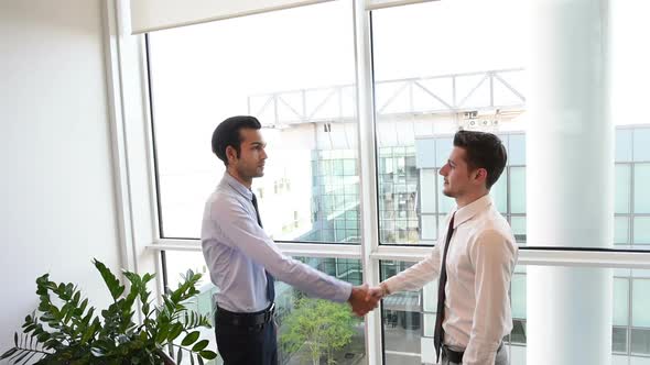 slow motion two young businessman indoor office interior shaking hands