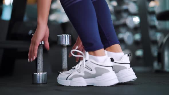 Woman taking dumbbells standing in gym