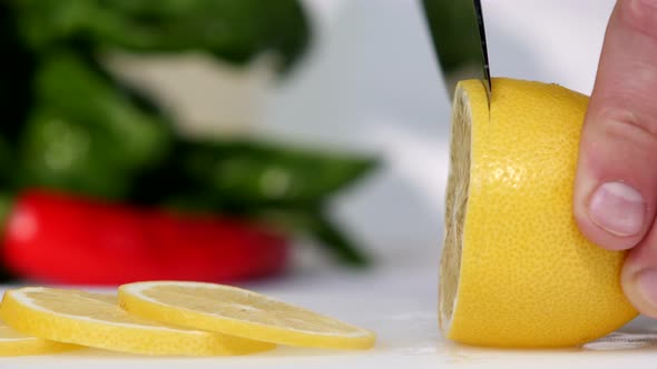 Knife a Cutting Juicy Lemon on a White Background