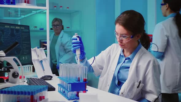 Scientist Nurse Using Micropipette for Filling Test Tubes