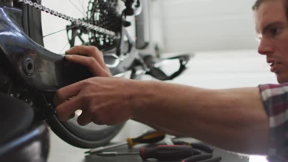 Focused caucasian man repairing bike using tools in garage