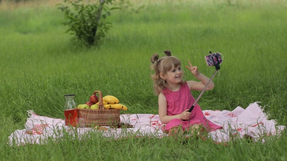 Weekend at Picnic. Girl on Grass Meadow Makes Selfie on Mobile Phone with Selfie Stick. Video Call