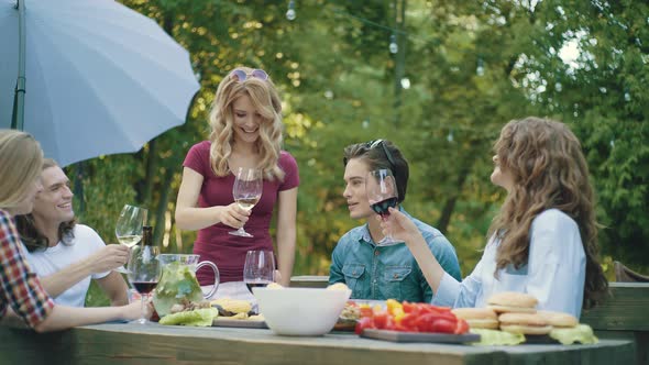 People Cheering With Drinks At Outdoor Dinner Party