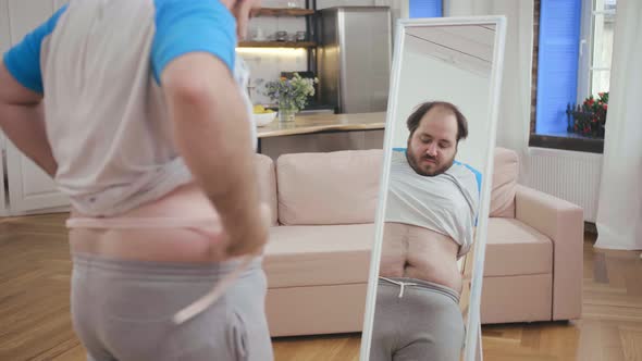 Fat Man with Measuring Tape Standing at Mirror