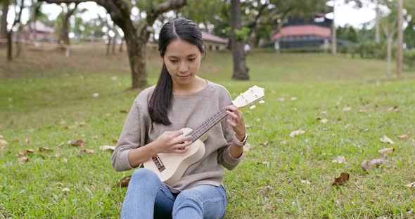 Young Woman enjoy play ukulele in the park