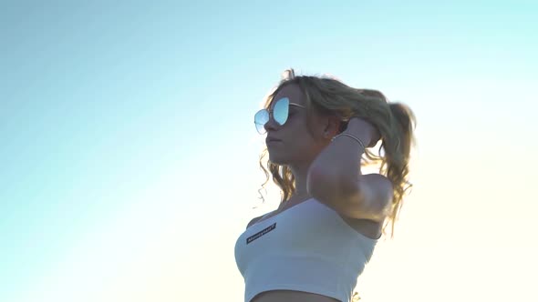 Sexy Blonde Girl Wearing Crop Top, Sunglasses, Lower Angle View. Sky Background