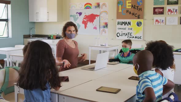 Female teacher wearing face mask teaching kids in the class at school